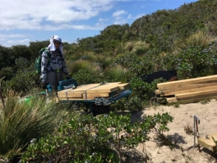 Jing moving timber and star pickets uphill with